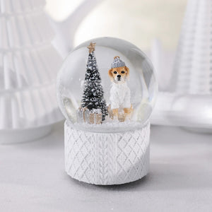 A ZODAX MOUNTAIN DOG WITH SWEATER SNOW GLOBE featuring a dog in a hat and sweater, a small Christmas tree, and gifts inside a resin glass ornament resting on a textured white base.