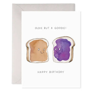The E. FRANCES - PB&J BIRTHDAY card by E. FRANCES PAPER features smiling peanut butter and jelly toasts on luxe heavyweight paper with the text "Oldie but a Goodie!" above and "Happy Birthday." Comes with an envelope.