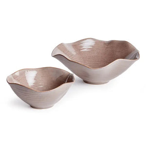 Displayed on a white background are two NAPA HOME AND GARDEN RIVO decorative bowls in beige with wavy, scalloped edges and glossy plum glaze, showcasing natural ceramic artistry. The bowls vary in size, with one being slightly larger.