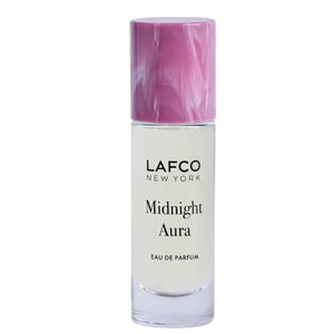 A person holds a 10ml bottle of LAFCO Fine Fragrance, Midnight Aura, on their bare shoulder against a soft purple background.