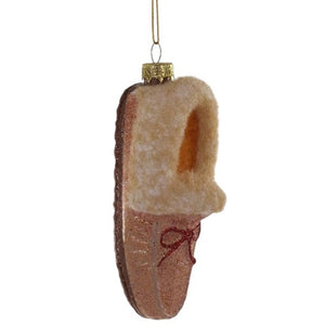 Cody Foster GLASS MOCCASIN ORNAMENT, a 1.5 x 1.5 x 3 inch tan glass moccasin slipper with a glittery finish and a red ribbon bow.
