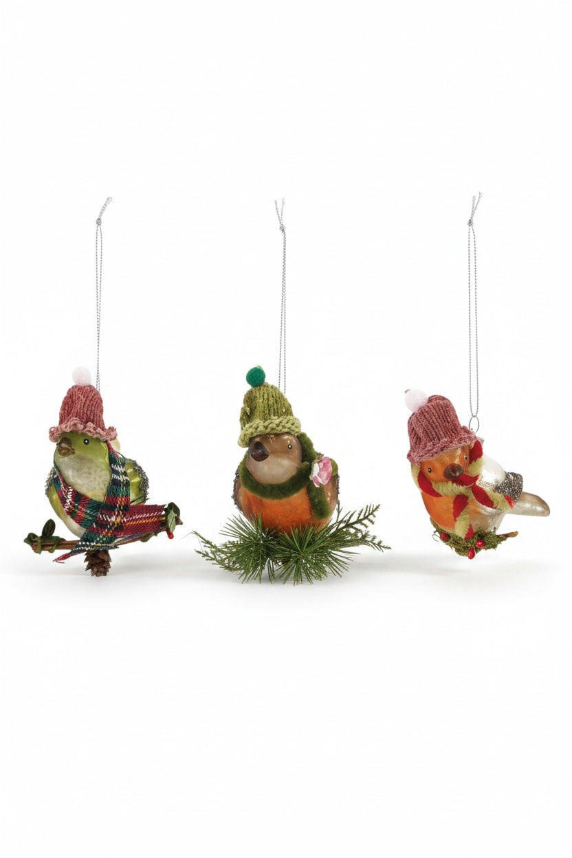 Three HAND PAINTED GLASS BIRD ON BRANCH ORNAMENT figures, each wearing a knitted hat and scarf while perched on a small branch.