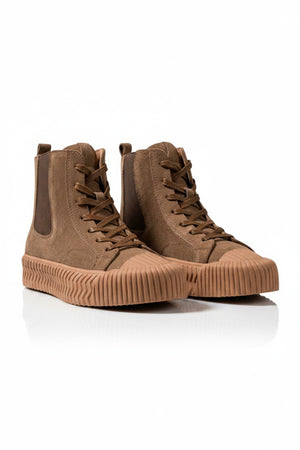The DANIELLA LEHAVI - OSAKA HIGH TOP SNEAKER features brown suede, tan ribbed rubber soles, and side elastic panels—a stylish and comfy choice from DANIELLA LEHAVI, shown on a white pedestal against a neutral background.