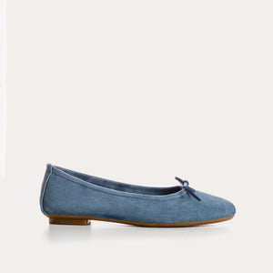 The REQINS Harmony Suede Ballerina Flats in Blue Jean feature luxurious goat suede, a delicate front bow, and a low brown heel, displayed on a plain white background.