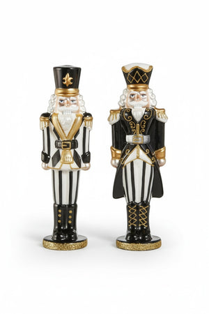 A hand places a BLACK AND WHITE NUTCRACKER with hand-painted embellishments next to an identical one on a marble countertop.