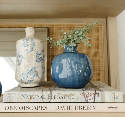 Two round, glossy blue ceramic NAPA HOME AND GARDEN - BLUE NARINE BUD VASES (Large) with narrow openings and crackle glaze patterns, positioned closely together on a plain white background.