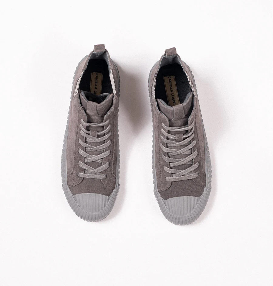 The DANIELLA LEHAVI - OSAKA HIGH TOP SNEAKER by DANIELLA LEHAVI features gray suede uppers and ribbed rubber soles, shown on a white pedestal against a plain light background. These stylish high-tops perfectly combine everyday comfort with modern style.
