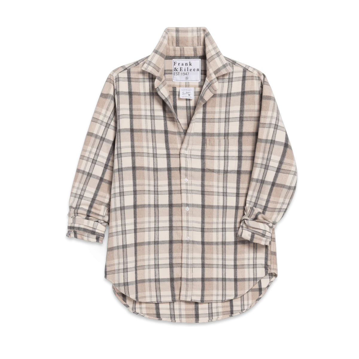 A woman smiles with her eyes closed, wearing the FRANK &amp; EILEEN EILEEN Relaxed Button Up Shirt in Italian Flannel Cream Sand Grey Plaid, paired with light gray sweatpants in a cozy room by a fireplace, with candles and books in the background.