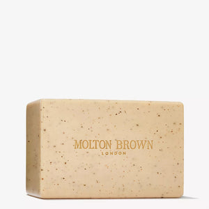 A rectangular beige MOLTON BROWN RE-CHARGE BLACK PEPPER BODY SCRUB BAR (250g) with small dark specks and "MOLTON BROWN LONDON" in gold across the front.