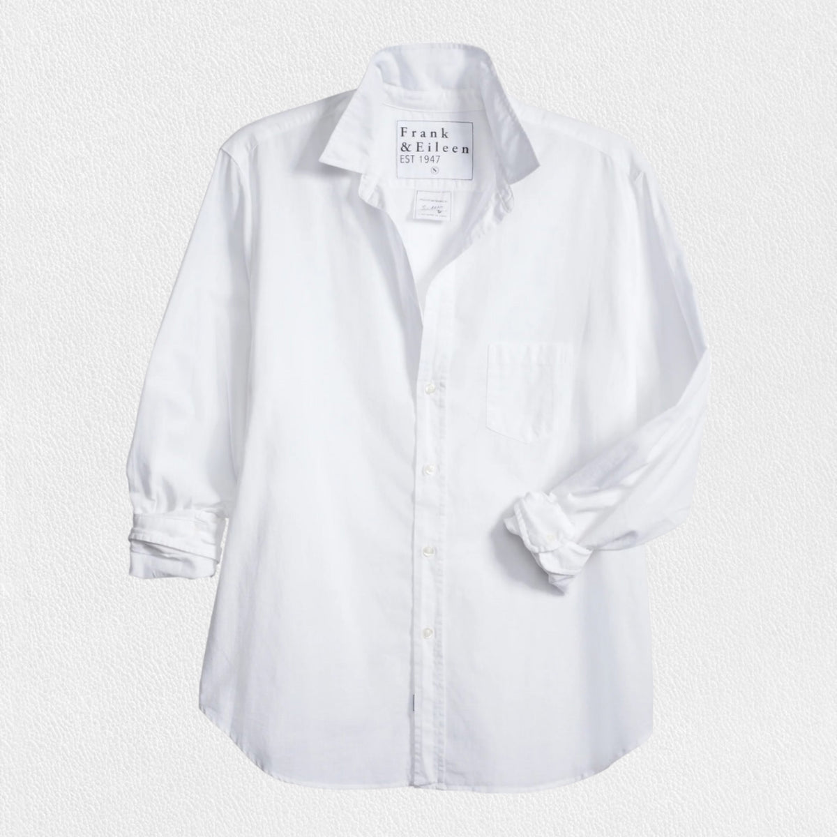 The EILEEN Relaxed Button-Up by Frank &amp; Eileen features a white chambray fabric with long sleeves, a chest pocket, and bust-flattering buttons. The collar displays "Frank &amp; Eileen EST. 1947," while the sleeves are slightly rolled for a casual look.