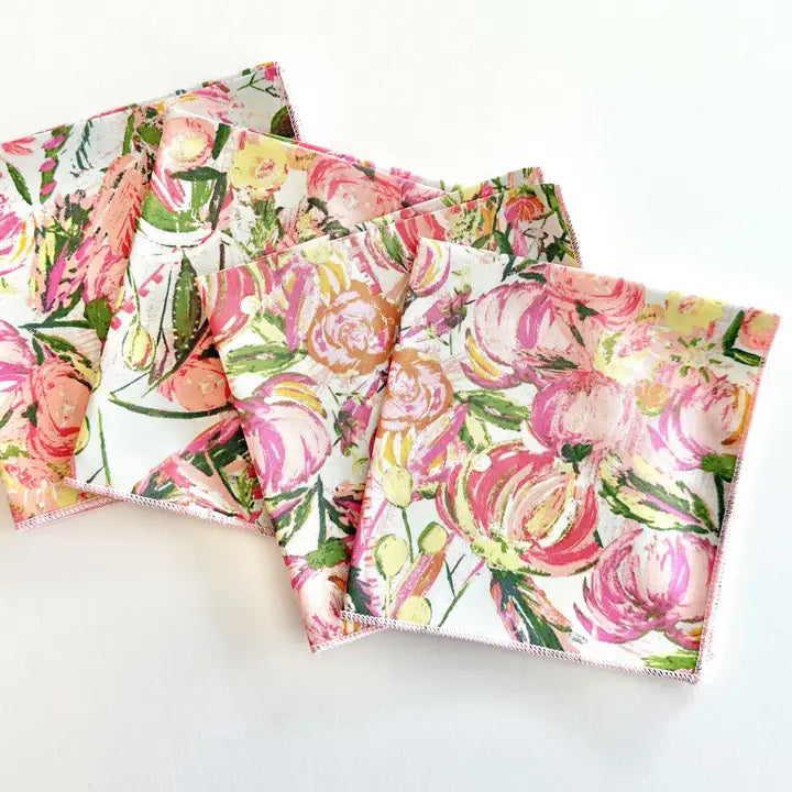The FLORAL FROLIC COCKTAIL NAPKIN set by DOT AND ARMY features four super soft cotton napkins with a pink, yellow, and green floral pattern, adding fresh color to your table and offering easy care for everyday use.