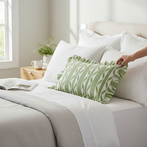 The LOOM & CLOTH IKAT Stripe Ruffled Lumbar Pillow in Green features a rectangular cotton design with green and white zigzag stripes, charming ruffled edges, and is set against a neutral background.