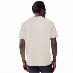 A man with short hair and a beard wears the MACK WELDON Heavyweight Slub Cotton Pocket T-Shirt in Froth, standing against a plain white background with his hands behind his back, looking at the camera.
