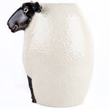 The QUAIL DESIGNS QUAIL CERAMICS - BLACK SUFFOLK SHEEP VASE, hand painted by artisans, displays a vibrant bouquet of white, purple, and maroon flowers with green foliage set against a white background.