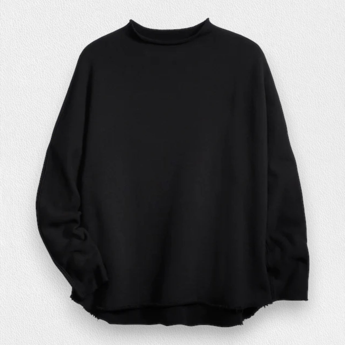 A woman with long brown hair stands smiling near a black grand piano in a modern, well-lit room. She wears the FRANK AND EILEEN - EFFIE LONG SLEEVE FUNNEL NECK CAPELET from FRANK &amp; EILEEN paired with blue jeans. A large window and a lamp are in the background, enhancing the cozy winter warmth of her stylish ensemble.