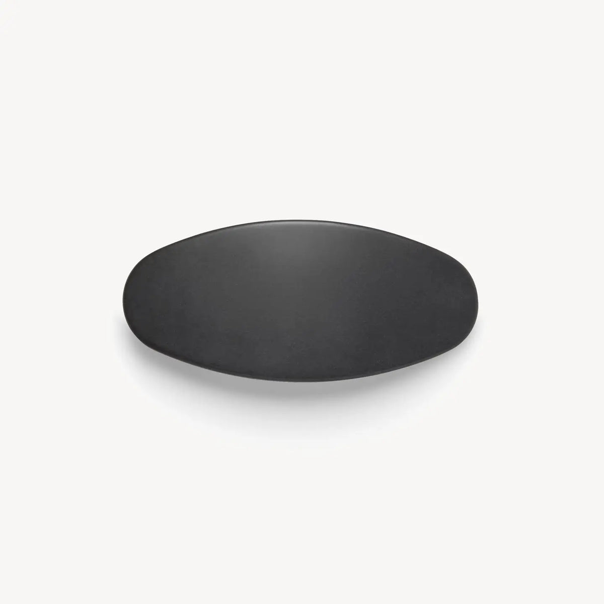 The MSCHETE - JUMBO OVAL BARRETTE IN MATTE BLACK by MACHETE is displayed against a plain white background, showcasing its simple, matte black, oval-shaped design reminiscent of a sleek oversized barrette.