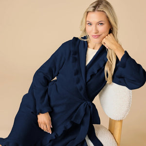 A woman wearing a SOFTIES - RUFFLE CHENILLE ROBE 36″ IN MIDNIGHT, a knee-length navy blue chenille robe with cascading ruffle trim.