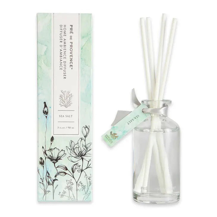 A glass diffuser bottle labeled &quot;European Soaps, LLC&quot; with white reed sticks stands next to its packaging box adorned with botanical illustrations and the text &quot;HERITAGE REED DIFFUSER - SEA SALT.&quot; A small tag reading &quot;Sea Salt&quot; is tied to one reed stick, showcasing the quality products made in France.
