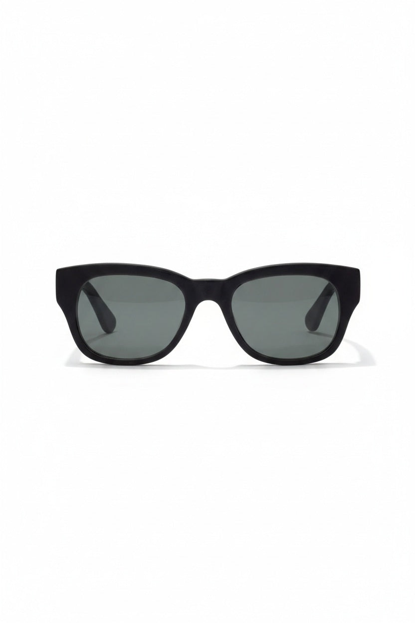 A pair of CADDIS - MIKLOS SUNGLASSES in matte black, featuring a premium bio-based acetate frame and grey polarized lenses, positioned at an angle to showcase the inside arm with the visible CADDIS brand name.