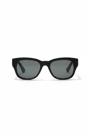 A pair of CADDIS - MIKLOS SUNGLASSES in matte black, featuring a premium bio-based acetate frame and grey polarized lenses, positioned at an angle to showcase the inside arm with the visible CADDIS brand name.