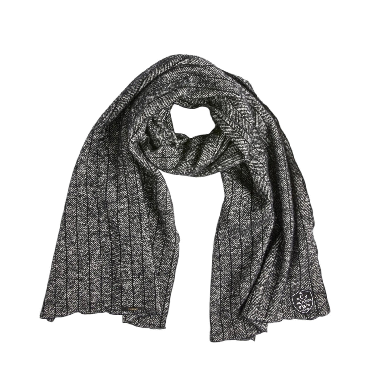 The CLIFTON WILSON - BLACK PINSTRIPE HERRINGBONE WOOL SCARF by CLIFTON WILSON, featuring a black pinstripe herringbone pattern in wool and a small embroidered patch at one end, is displayed flat against a white background.