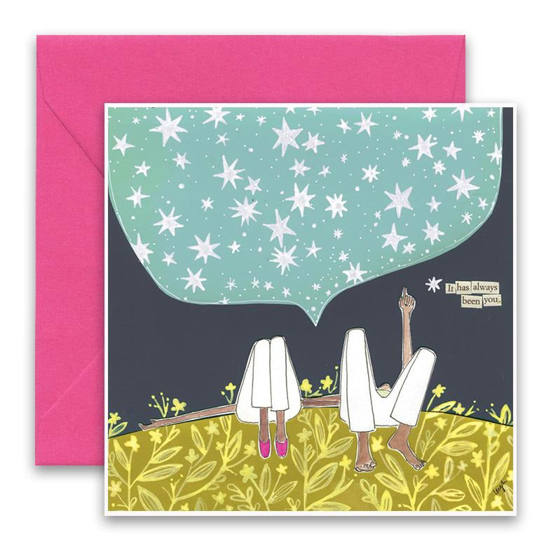 The Curly Girl Designs - Always Been You Card by Curly Girl Design, Inc. features an illustrated scene of two people sitting on a grassy field at night, pointing at the starry sky depicted within a speech bubble. The text reads "It has always been you." One person is adorned with pink shoes, creating a subtle color contrast, while a bright pink envelope in the background enhances the collage art appeal.