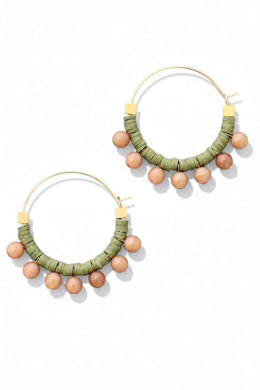 The DAVID AUBREY - GREEN AND PEACH HOOP EARRINGS by DAVID AUBREY feature gold plated hoops adorned with green polymer discs and round peach beads hanging along the bottom, shown against a flat gray background.