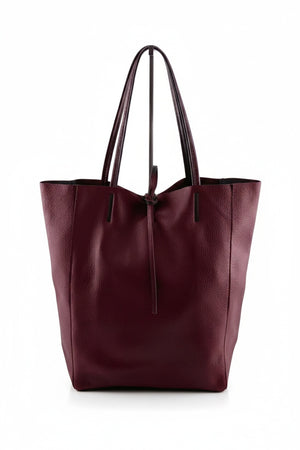 Introducing the LEATHER TOTE BAG IN DARK WINE by JIJOU CAPRI—a spacious Italian leather tote in a deep wine hue, designed with two strong handles and a convenient drawstring closure, ideal for carrying your daily essentials. Shown against a plain white background.
