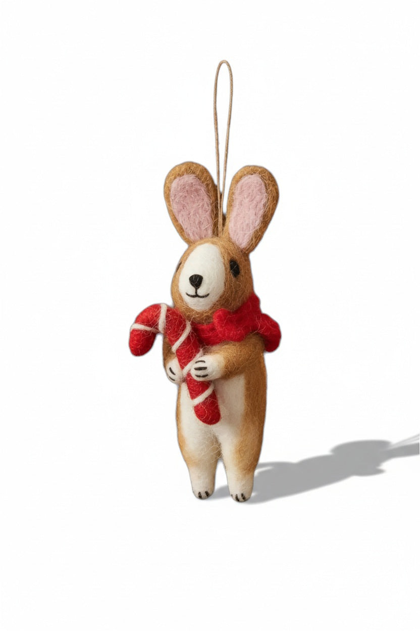A CINNAMON RABBIT ORNAMENT by FELT SO GOOD hangs on a Christmas tree decorated with a felt rabbit, a candy cane, dried orange slices, and pinecones.