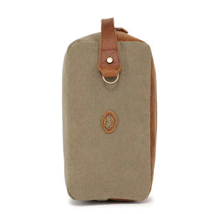 The TSD BRAND Valley Oak Toiletry Bag in olive is a rectangular, handcrafted travel essential made from durable canvas, featuring a tan leather strap and a small leather patch for added style.