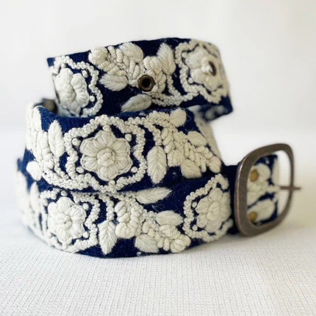 The JENNY KRAUSS Two Toned Belted in Blue and Cream features intricate embroidery, a silver rectangular buckle, and is handcrafted in Peru. Shown coiled on a white surface.