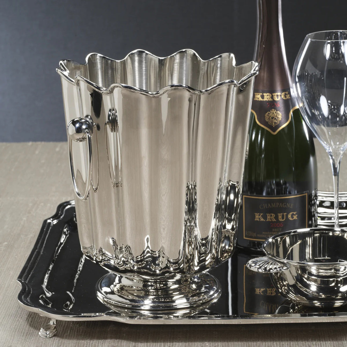 The ZODAX ORLEANS Wine or Champagne Bucket is a shiny silver piece with vertical ridges, scalloped edges, two round side handles, and stands 9 inches tall—an elegant decorative item shown on a white background.