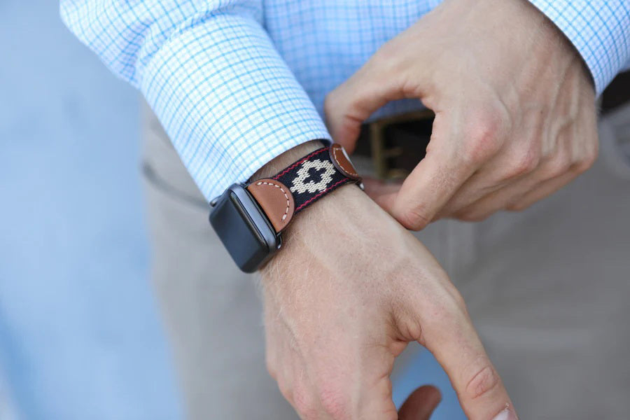 The LA MATERA CORBINA Apple Watch Band features an artisan-made brown leather band with a black woven strap and beige diamond pattern, displayed on a white background.