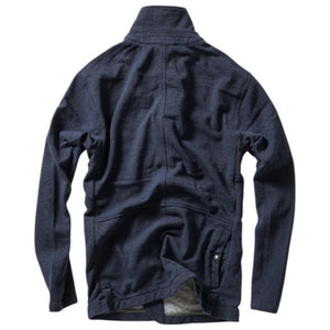 A person wearing the RELWEN - PIQUE TRAP BLAZER IN NAVY HEATHER over a checked shirt and green cargo pants stands with hands in pockets against a plain background, showcasing the blazer’s relaxed fit.