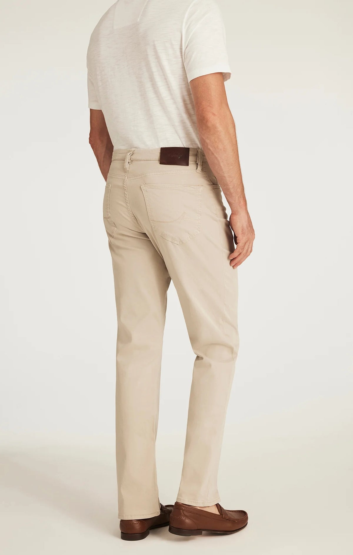 A man with light brown hair and a beard wears a tan blazer, brown sweater, white collared shirt, 34 HERITAGE - CHARISMA RELAXED STRAIGHT LEG PANT IN DAWN TWILL by 34 HERITAGE, and brown shoes against a plain white background.