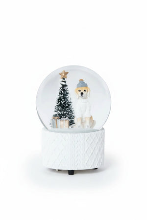 A ZODAX MOUNTAIN DOG WITH SWEATER SNOW GLOBE featuring a dog in a hat and sweater, a small Christmas tree, and gifts inside a resin glass ornament resting on a textured white base.