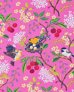A person wearing a PRINTFRESH - BIRD & BLOSSOM LONG ROBE IN FUSCHIA, a long organic cotton robe with a bird and blossom pattern and green and white striped trim.