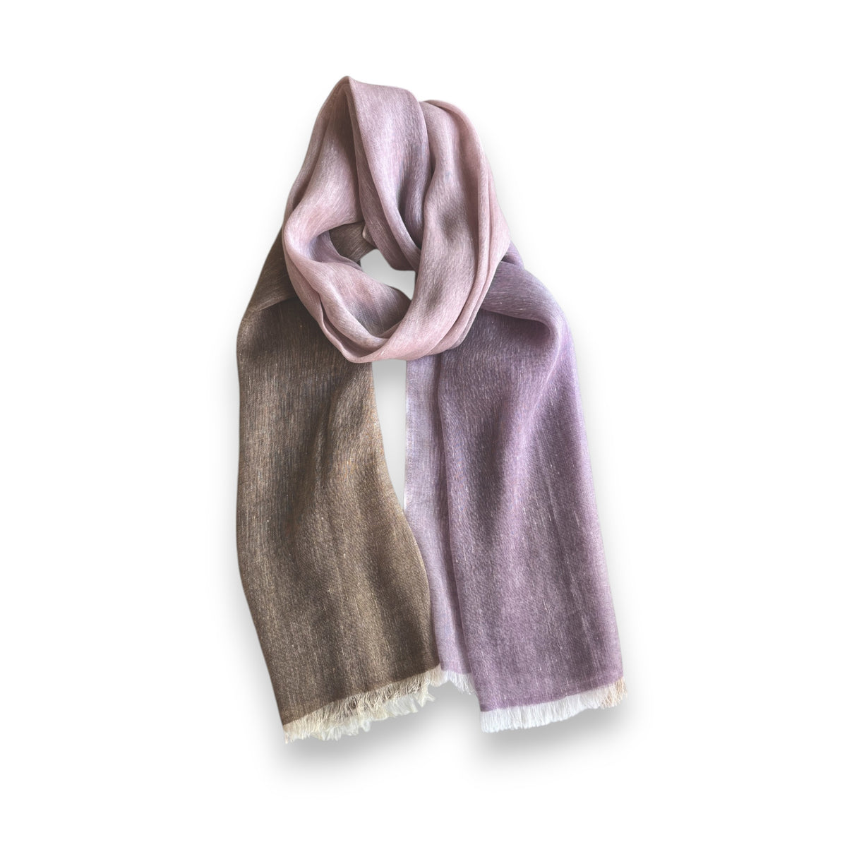 The BAJRA Hand Dyed Linen Blend Scarf in Plinth Brown Ombre showcases a color gradient from pink to purple to brown, elegantly looped against a white backdrop. This handmade piece features fringed edges and embodies the warmth and craftsmanship of Nepal.