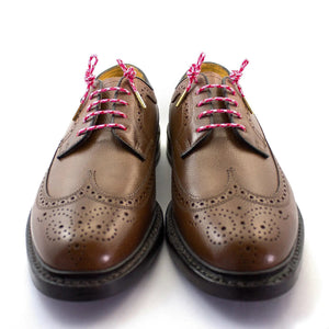 STOLEN RICHES - DRESS SHOELACES IN CAMO PINK: Premium pink and white camo-patterned laces with gold tips, bundled and wrapped in a white label reading “Stolen Riches Since 1915” with a crown logo.