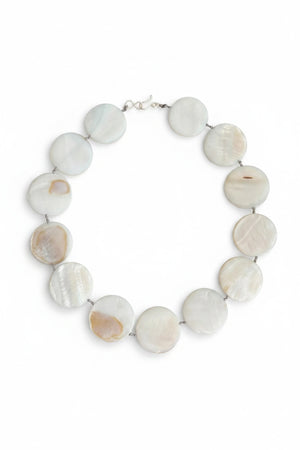 A mannequin is styled with a light gray shawl and showcases the ANN LIGHTFOOT Mother of Pearl Disc Ras du Cou Necklace, featuring large, round white beads and a sterling silver clasp, set against a neutral brown background.