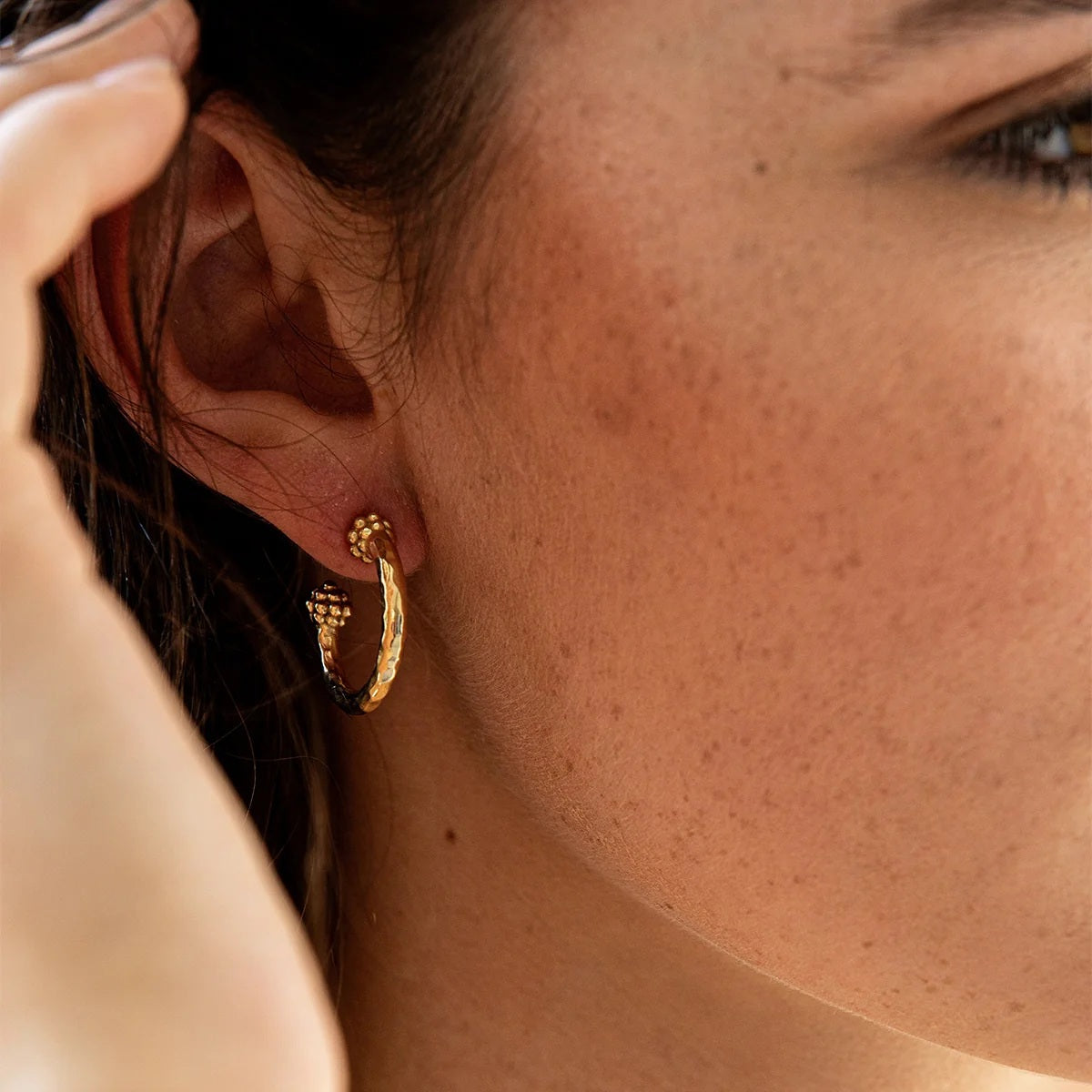 The CAPUCINE DE WULF - BERRY SLICE SMALL HOOP EARRINGS by CAPUCINE DE WULF feature a handmade design with small gold hoops, showcasing a textured hammered finish and decorative beaded clusters at the top and bottom of each hoop, displayed on a white background.