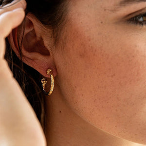The CAPUCINE DE WULF - BERRY SLICE SMALL HOOP EARRINGS by CAPUCINE DE WULF feature a handmade design with small gold hoops, showcasing a textured hammered finish and decorative beaded clusters at the top and bottom of each hoop, displayed on a white background.