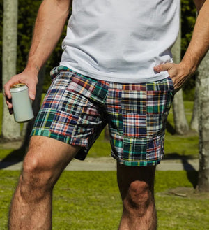 The CRIQUET Cruiser Shorts in Navy Madras feature a colorful plaid patchwork, elastic waistband with white drawstring, and are crafted from 100% cotton for comfort and style.