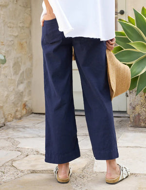 The FRANK & EILEEN Wexford Wide Leg Linen Pant in Navy is showcased against a light textured background. These high-rise trousers, crafted from Italian Performance Linen, feature a flat front and straight hem with a clean and minimalist design, absent of visible pockets or embellishments.
