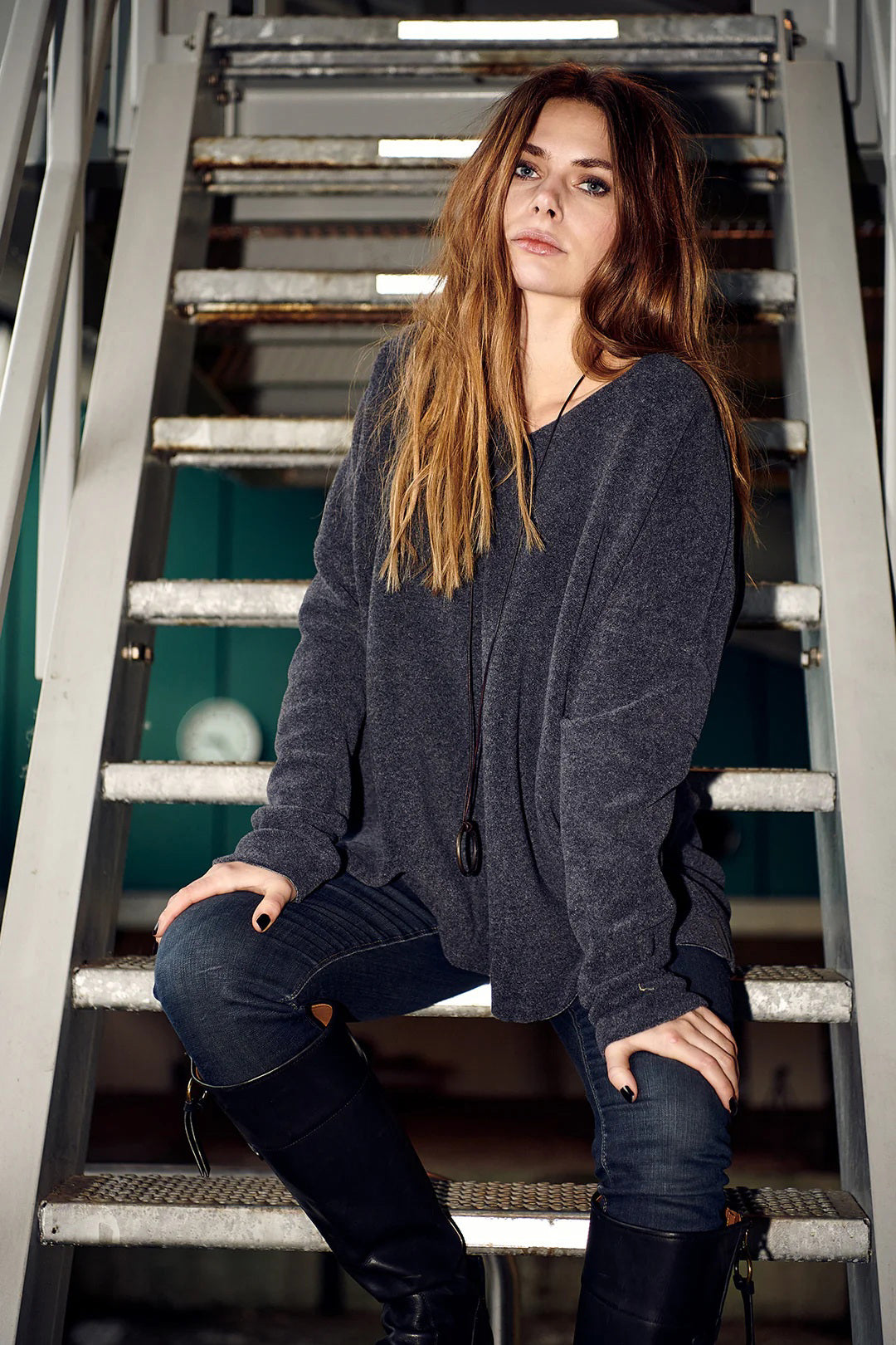 The HENRIETTE STEFFENSEN FLEECE V NECK SWEATER by HENRIETTE STEFFENSED is a loose-fitting, long-sleeve black sweater with a cozy V-neck, shown on a hanger and styled with a circular pendant necklace.