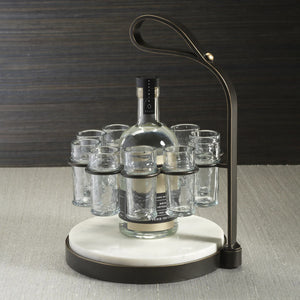 The ZODAX TEQUILERO 10 Shot Tequila Set features a circular white marble cutting board with an iron handle and metal frame, holding ten empty shot glasses arranged in a ring.