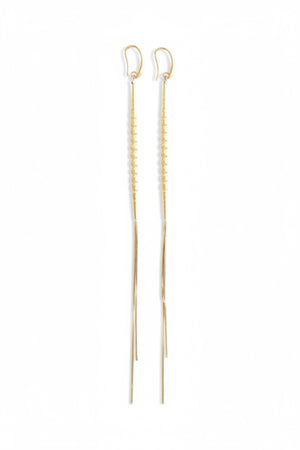 DAVID AUBREY - GOLD PLATED SHOULDER DUSTER EARRINGS feature small round beads and delicate gold-plated chain ends, elegantly displayed on black hexagonal tiles set against a gray background.