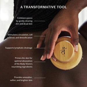 The KATE MCLEOD - THE DRY BRUSH, featuring natural bristles, is displayed on a beige towel atop marble, accented with an orange flower—evoking a relaxing dry brushing and lymphatic drainage ritual.