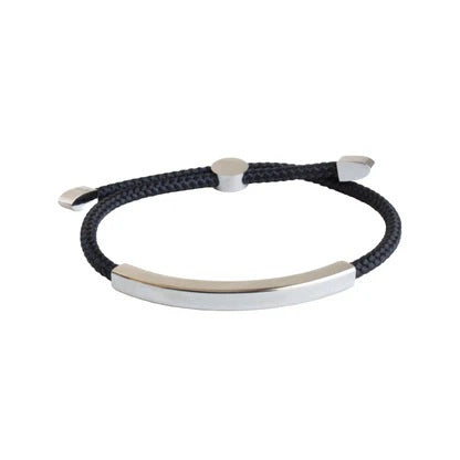 The STOLEN RICHES Algarve Bracelet in black features a braided cord with a sleek silver bar, silver end caps, and an adjustable sliding clasp for a minimalist look.