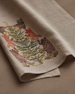 TINSEL TREE LINEN TEA TOWEL by CORAL & TUSK featuring embroidered owls, foxes, and bears decorating a tinsel tree for holiday decor.